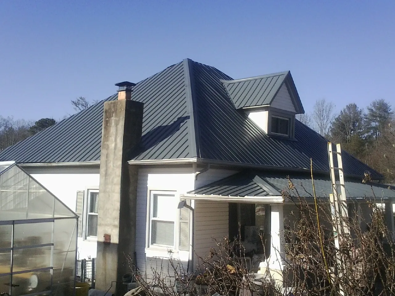 Dark blue standing seam metal roof on a white farmhouse with dormer — Slate & Tile Roof Repair by Roofing Brothers in Sardinia
