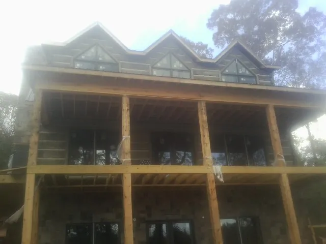 Dormers and porch framing on a large log home under construction — Roof Coating work by our crew in Sardinia