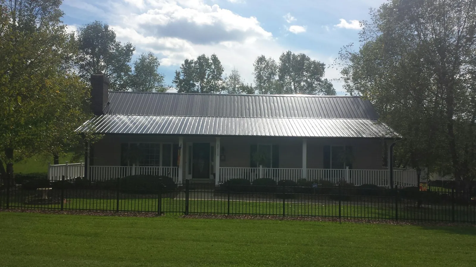 Gray metal roof on a brick ranch with a full width front porch — Gutter Guard Installation work by our crew in Sardinia