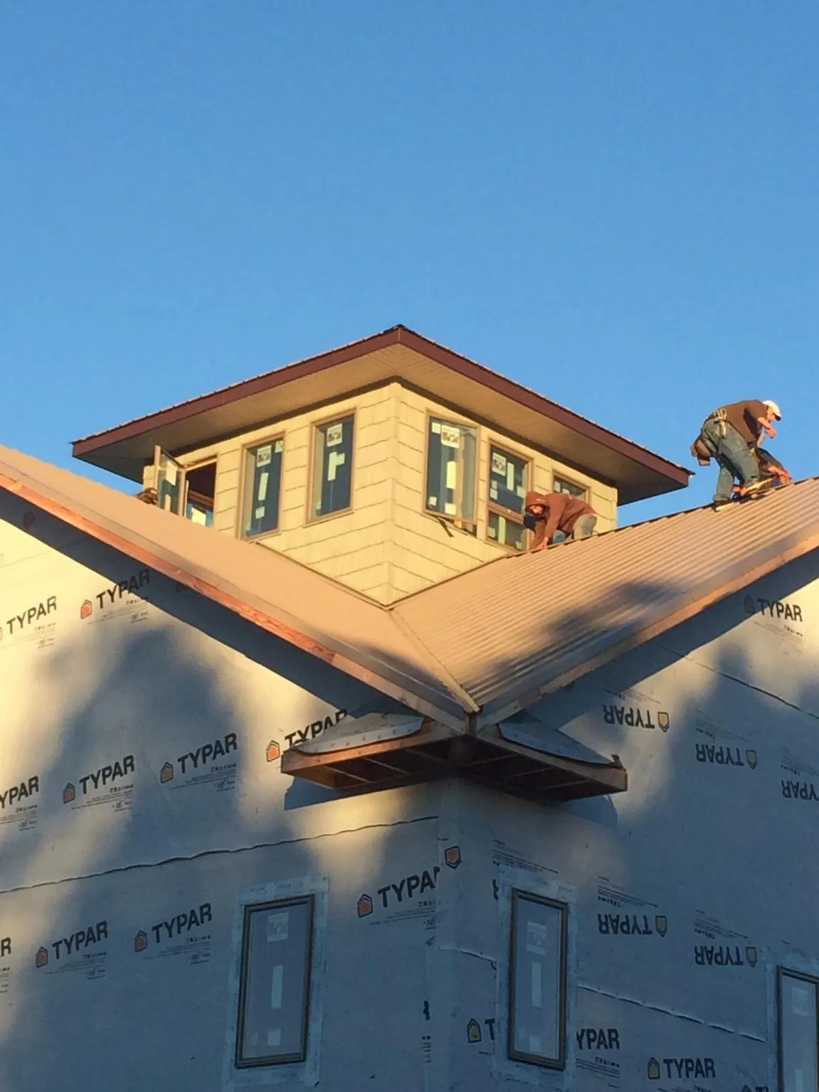 Roofers working around a rooftop cupola on a new metal roof at sunset — Roof Waterproofing in Sardinia by Roofing Brothers